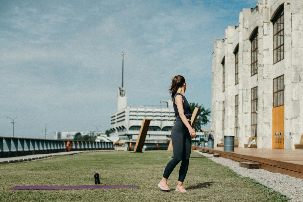 A woman performs exercises outdoors by an architectural building in Saint Petersburg, showcasing a healthy lifestyle.