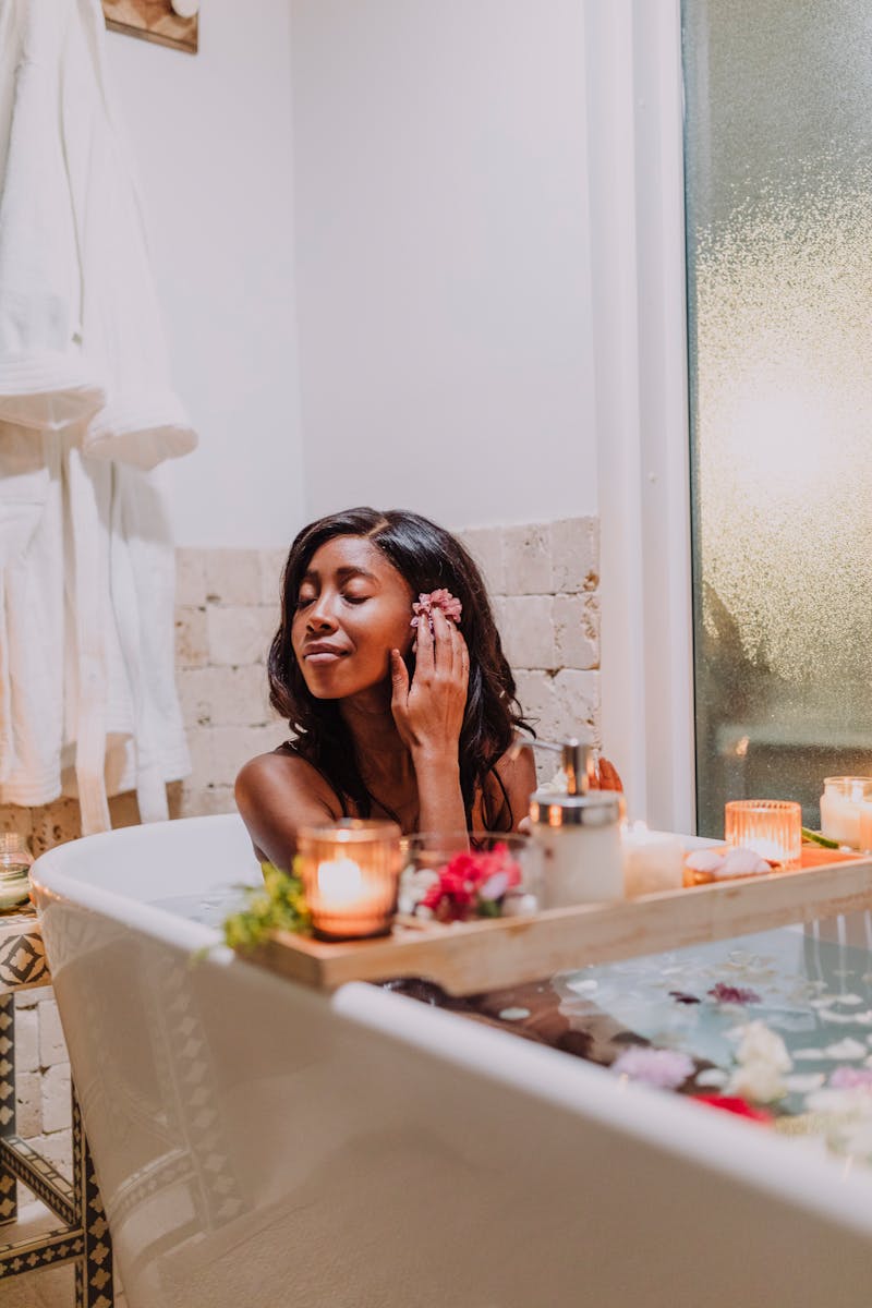 Woman enjoying a relaxing bath with candles and spa essentials for self-care and relaxation.