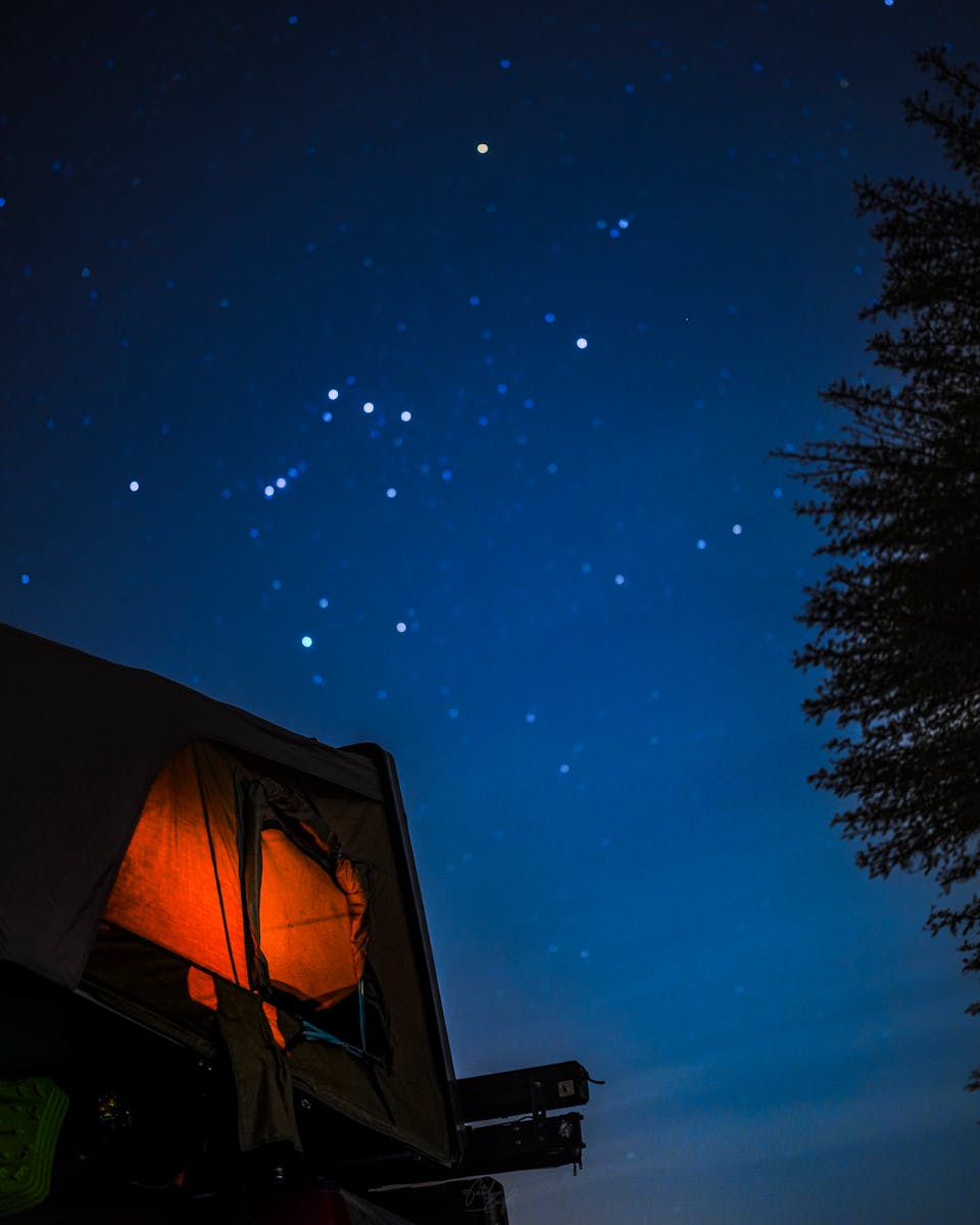 A glowing tent under a vivid night sky with starry constellations, ideal for travel themes.